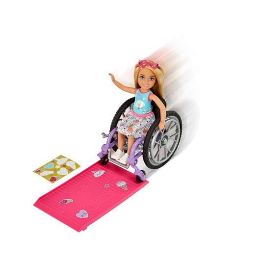 Barbie - Chelsea bambola bionda con sedia a rotelle, che indossa gonna e occhiali da sole, include rampa e foglio adesivi - 2